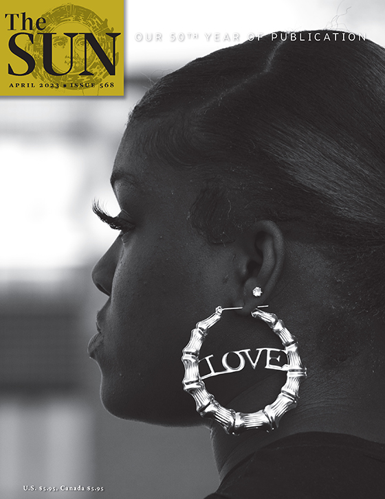 April 2023 cover of The Sun. Close-up profile of a woman’s face. She is wearing a large hoop earring with LOVE in metal spanning the middle. She is watching a fraternity/sorority step show at Livingstone College, an HBCU in Salisbury, North Carolina.